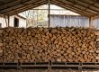 Grande pile de bois de chauffage fendu, soigneusement rangée sur palettes sous un abri en bois pour un séchage optimal.